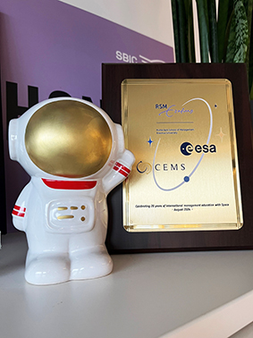 commemorative plaque for ESA/CEMS on shelf next to space-themed figurine 