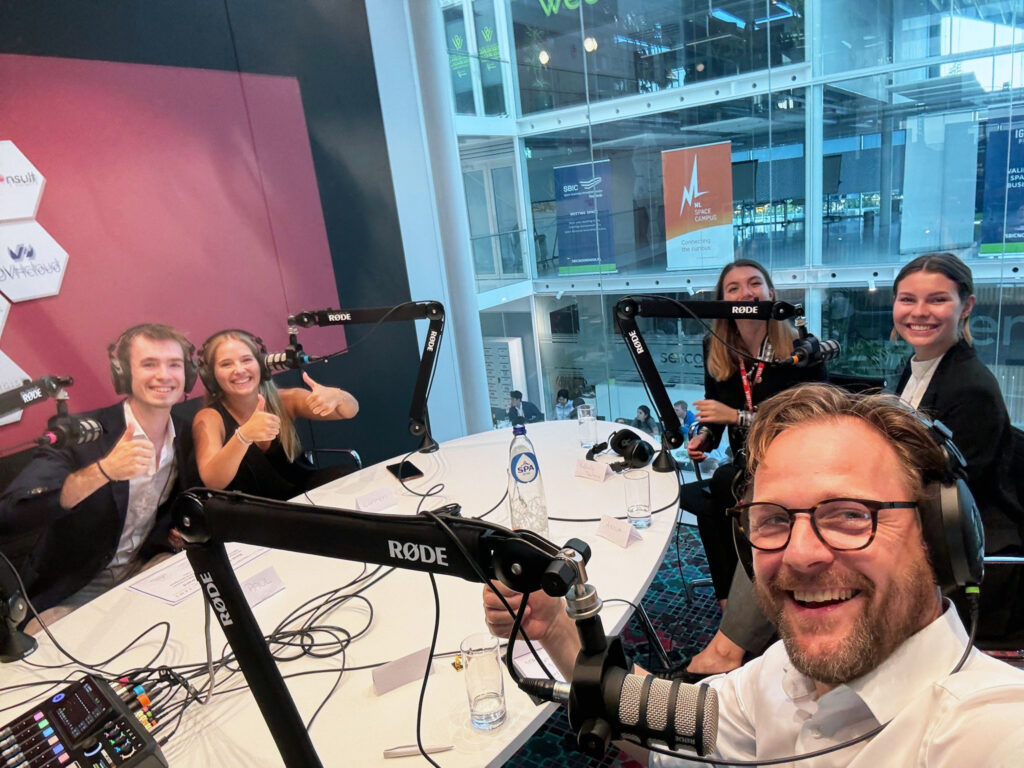 business professionals at an oval table with podcast equipment