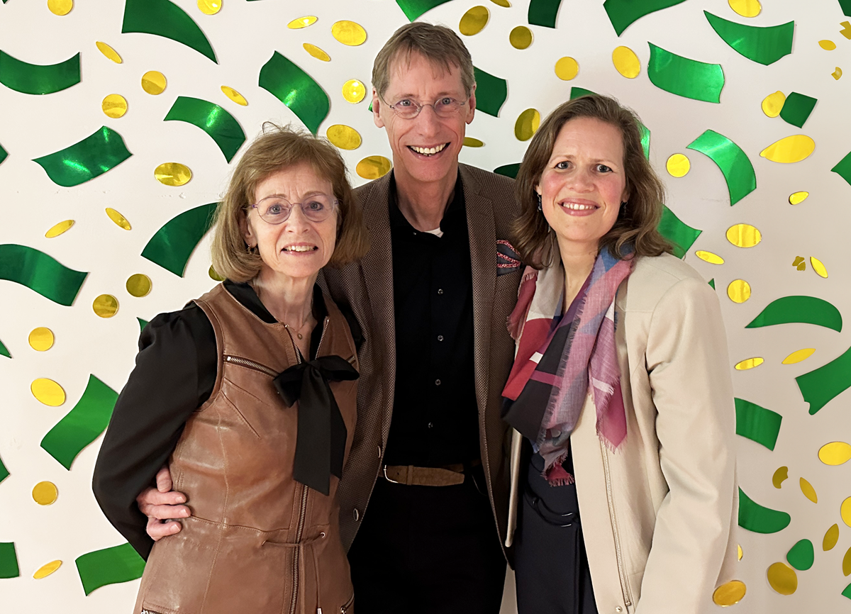 Three people stood in front of a wall with patterned design